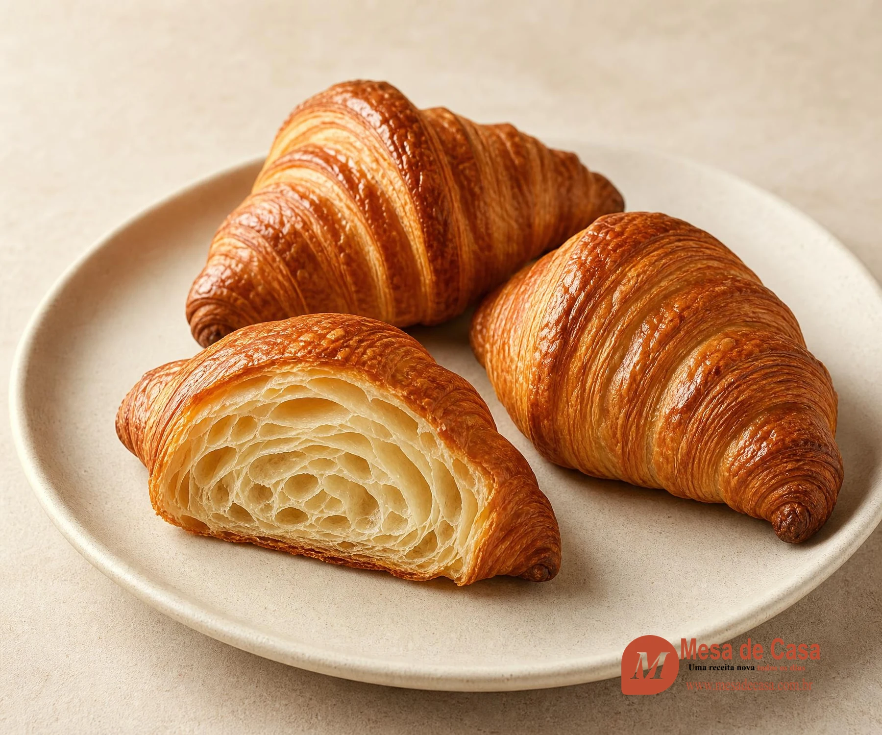 Croissants dourados com um cortado revelando camadas e alvéolos internos