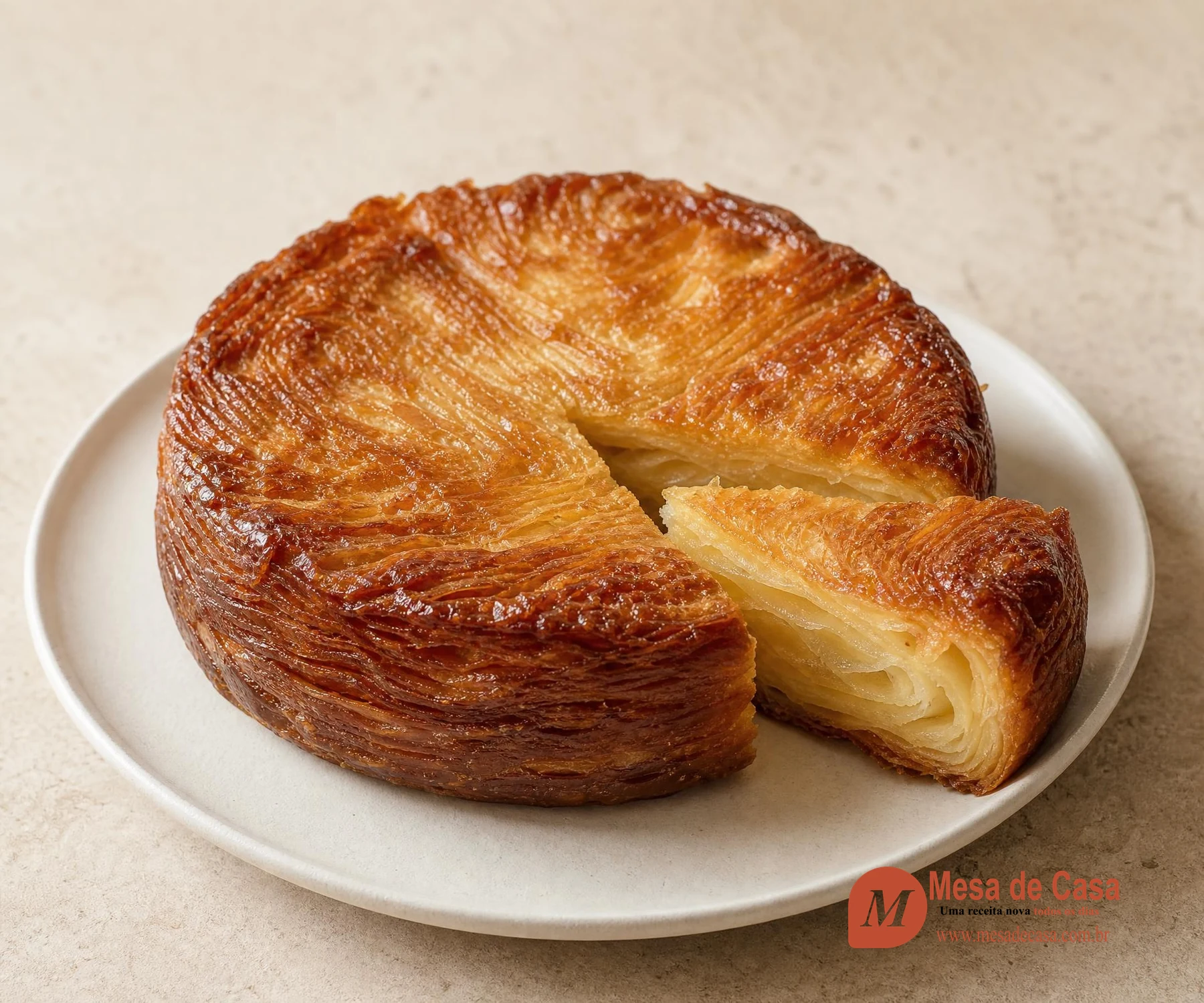 Kouign-amann bretão redondo com bordas caramelizadas e fatia revelando camadas