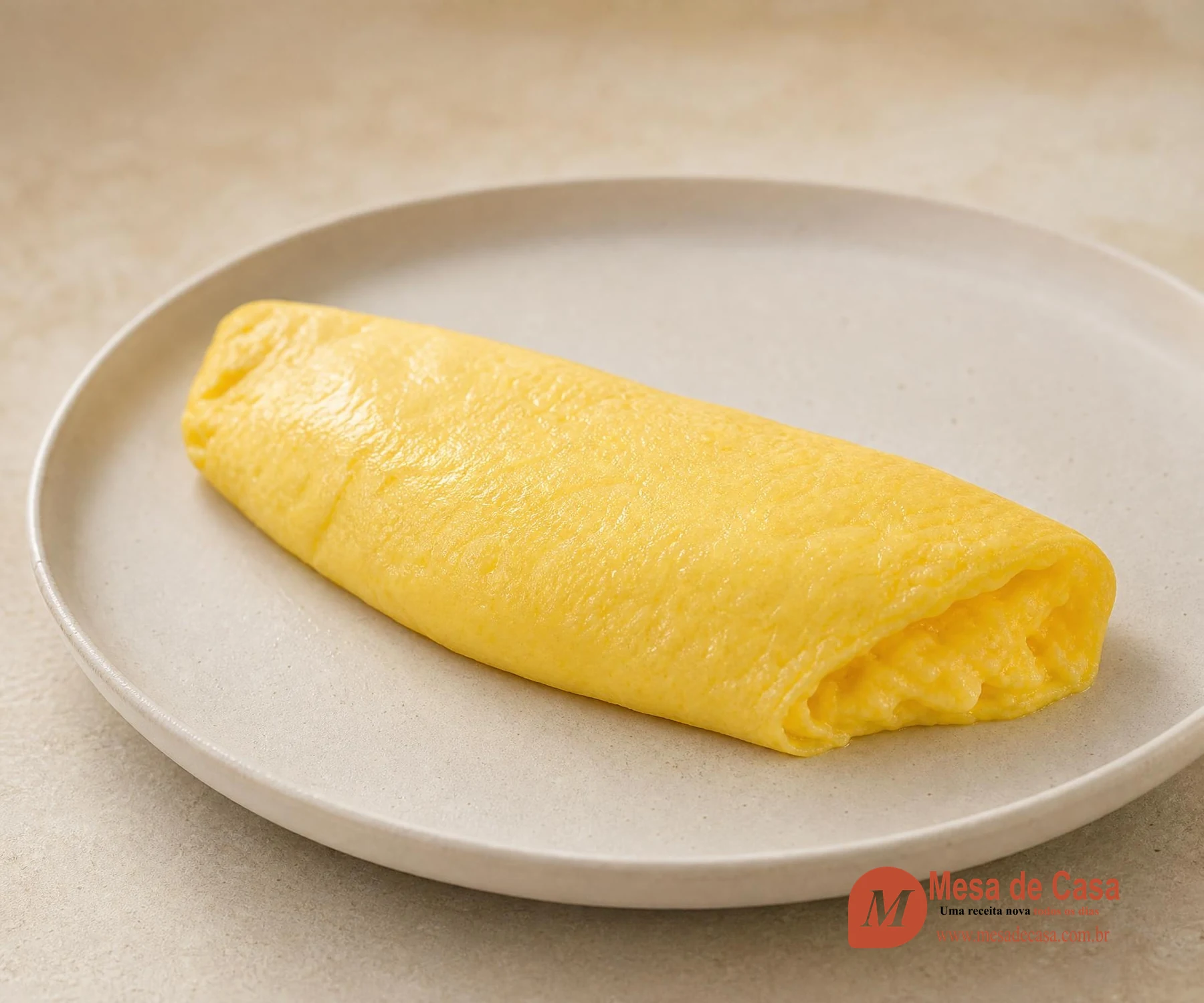 Omelete francesa lisa e amarela dobrada sobre prato claro