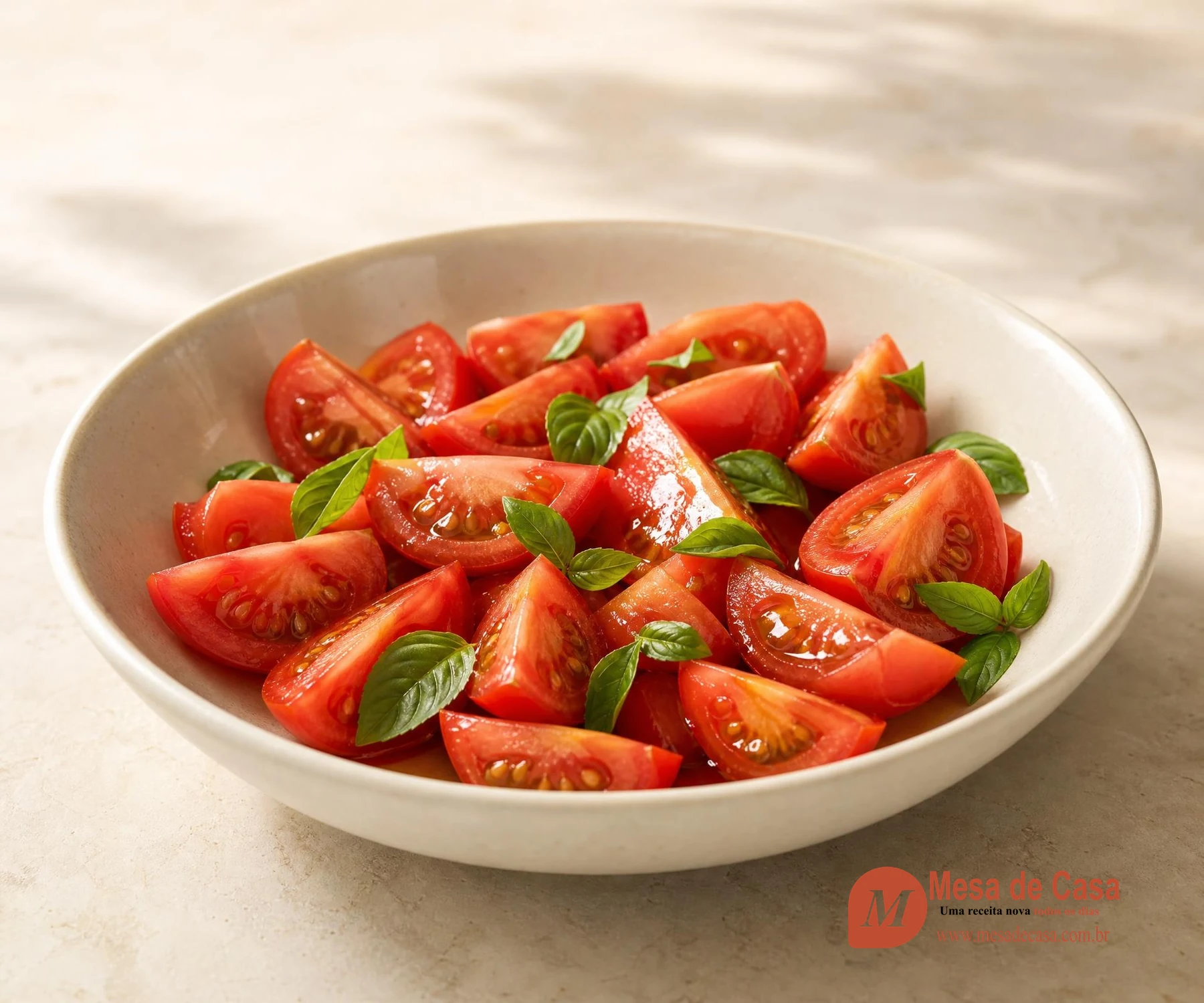 Gomos de tomate maduro com azeite e folhas frescas de manjericão em tigela clara