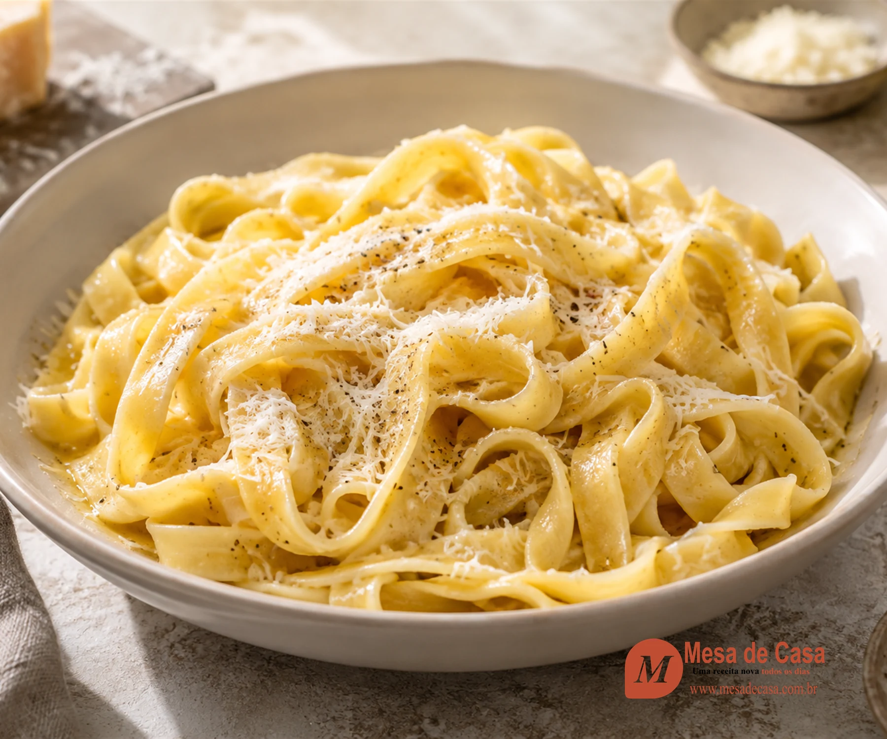 Fettuccine fresco em fitas largas, brilhante de manteiga e coberto por parmesão fino