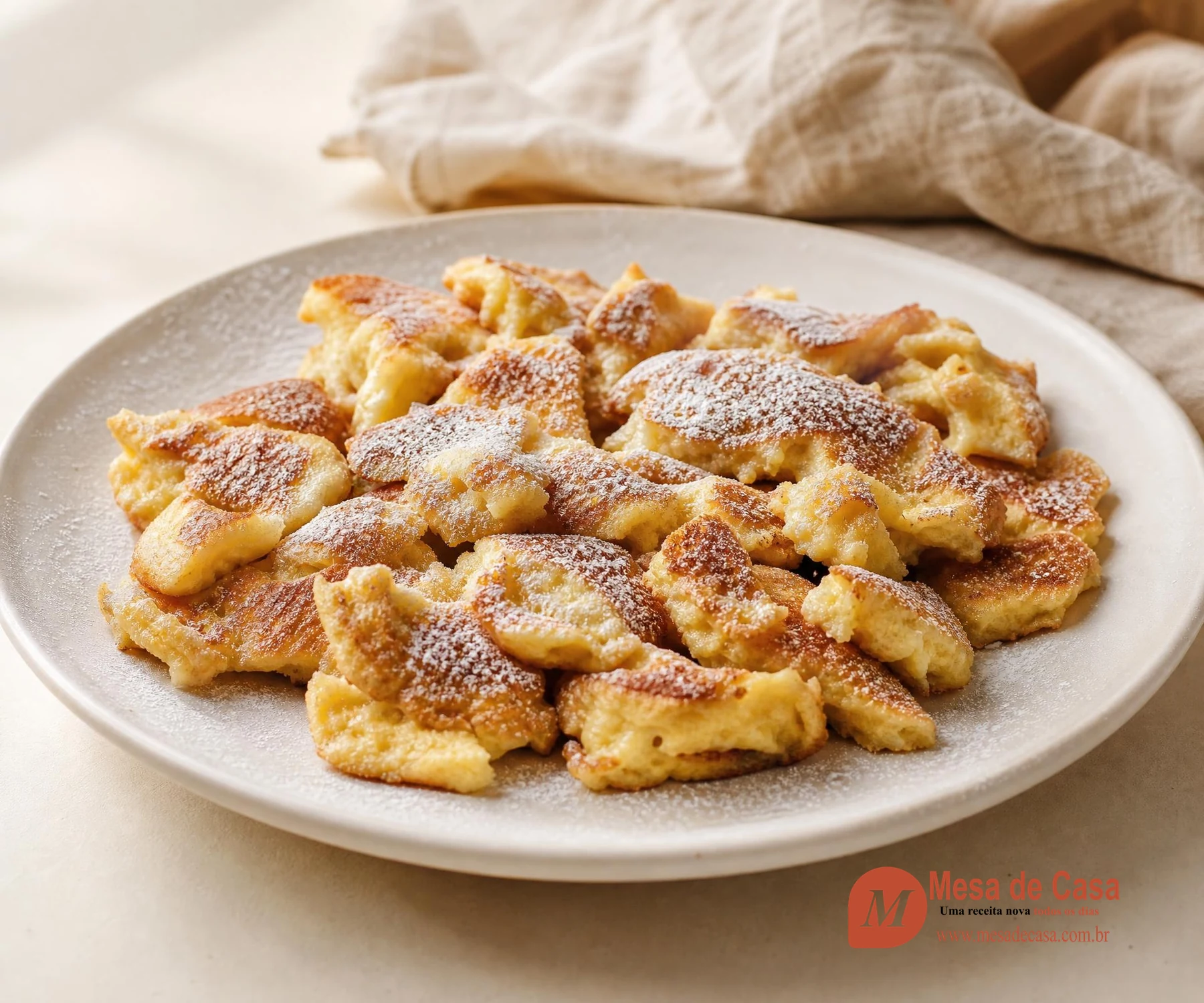 Kaiserschmarrn dourado em pedaços irregulares, com interior fofo e fina camada de açúcar